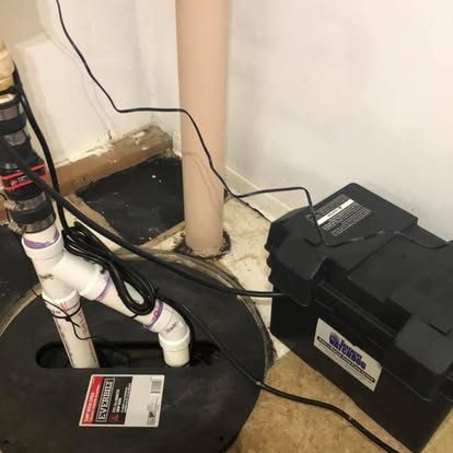 A sump pump with battery backup installed in a basement pit.